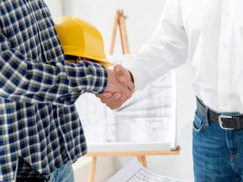 Professional contractor and client shaking hands after reviewing a service agreement