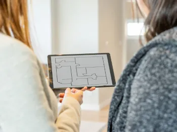 Professional reviewing a residential floor plan with a client on a tablet