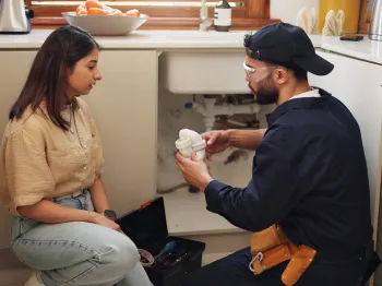 Professional plumber explaining a home plumbing repair to a customer