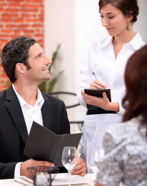 Professional restaurant server assisting customers at their table
